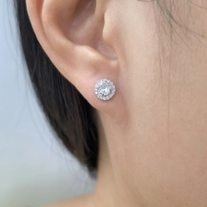 Macro shot of elegant S925 silver round halo stud earrings worn on ear featuring sparkling cubic zirconia
