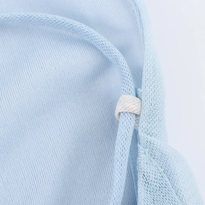 Détail macro de la bretelle bleu clair et de l'anneau blanc sur la robe en maille