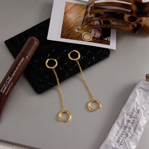 Vue détaillée des boucles d'oreilles à chaîne dorée avec double anneau sur un décor chic