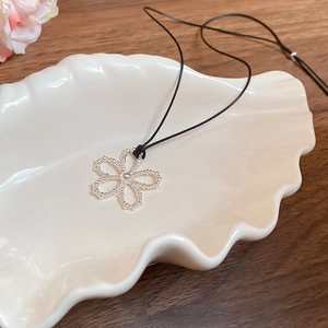 Détail d'un pendentif fleur argenté avec texture perlée sur un cordon noir élégant