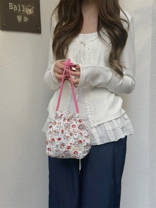 Detailed view of hand-held floral quilted drawstring pouch with pink rope handles