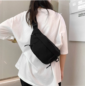 Street style black nylon chest bag with adjustable strap worn on back in lifestyle setting