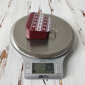 Macro shot of a red tin gift box with reindeer patterns on a kitchen scale weighing 30.8g