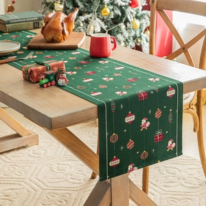 Runner da tavola natalizio verde con motivi di Babbo Natale su un tavolo di legno