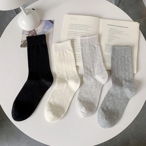 Close-up of four colors breathable mesh cotton mid-calf socks on a white minimalist table