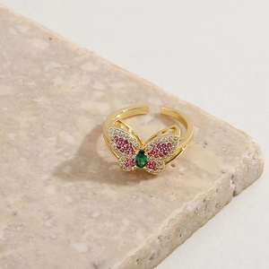 Adjustable gold plated butterfly ring with pink and green zircon on marble base