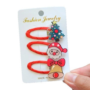 Close-up of Christmas hair clip set with resin tree, Santa Claus, and golden bell motifs