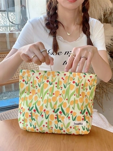Canvas makeup bag with green floral tulip print and Sozakka label in a lifestyle setting