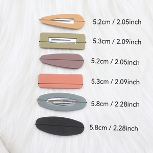Size measurements of colorful matte geometric hair clips on a white plush surface