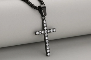 Macro shot of a black cross pendant with sparkling pave-set clear zircon stones on a chain