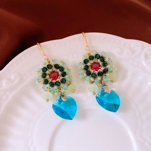 Dettaglio macro di orecchini vintage con fiori di perline e cristallo a cuore blu