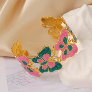 Detail of pink and green enamel butterfly on a gold-plated open bangle with satin finish