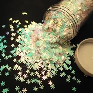 Macro shot of iridescent snowflake-shaped sequins for nail art in a clear plastic jar