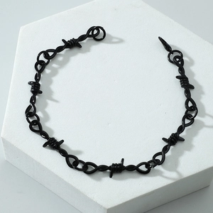Bracciale unisex in filo spinato nero su espositore bianco in stile punk rock
