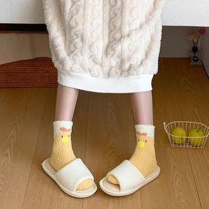 Close-up of fluffy yellow chicken socks with coral fleece and white indoor slippers