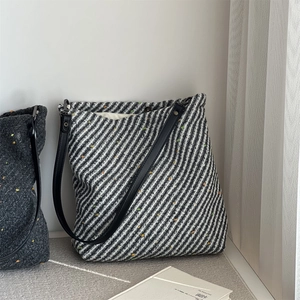Close-up of thick tweed tote bag with black and white twill pattern and leather straps