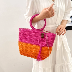 Pink and orange gradient woven straw tote bag with round handles and tassel details