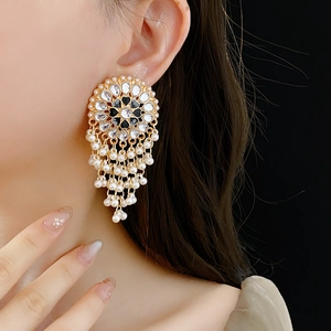Detail of vintage gold earrings with rhinestones, black stones and pearl tassels