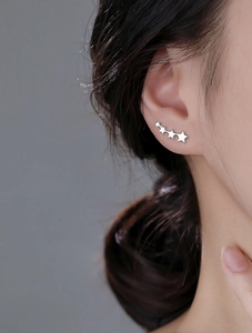 Dettaglio degli orecchini a lobo con stelle in argento dal design curvo ed elegante