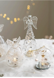 Close-up of glass angel Christmas ornament with warm LED light and white snowflake patterns