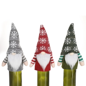 Three Christmas gnome wine bottle covers in red, grey, and green with snowflake patterns