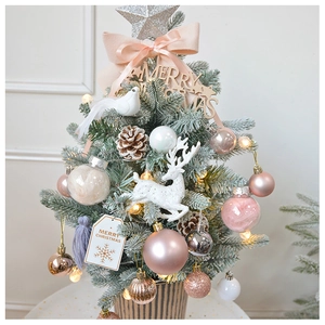 Detailed close-up of a decorated mini Christmas tree with pink ribbons and wooden base