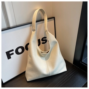 Close-up of cream lychee texture leather tote bag leaning against a decorative frame