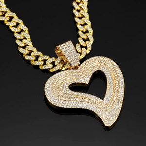 Detailaufnahme eines goldfarbenen Herzanhängers mit Diamantbesatz an einer Kuba-Kette