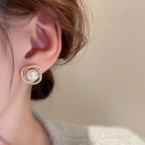 Macro d'une boucle d'oreille en or avec zircons entourant une perle blanche