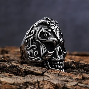 Vintage punk skull ring in stainless steel with intricate scroll engraving on wood