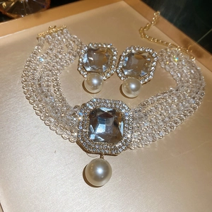 Detailed macro view of multi-layer pearl choker set with square crystals and diamond accents