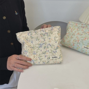 Detailansicht der Stoffstruktur und des Markenetiketts der floralen Leinwand-Kosmetiktasche