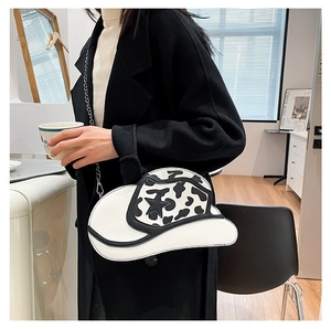Detail of cowboy hat shaped shoulder bag featuring cow print and star accent