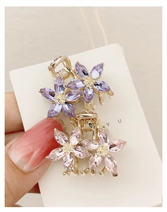 Close-up of small floral crystal hair claws in pink and purple on display card
