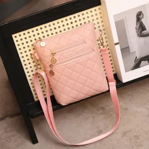 Detail of pink quilted crossbody bag with dual golden zippers and rhombus pattern