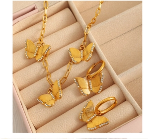Close-up of golden butterfly necklace and earrings set with zircons in a pink velvet box
