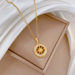 Detail of gold starburst compass pendant with crystal halo on beige velvet box and silk