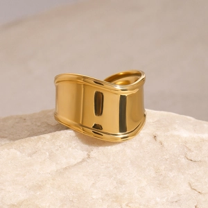 Polished 18K gold-plated irregular wavy wide open ring on a natural stone base