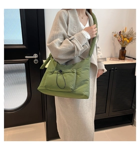 Detail of green quilted puffer tote bag with drawstring pocket and padded strap