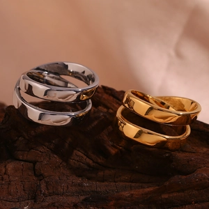 Detailed view of silver and 18K gold double-layered cross rings on a textured wooden base