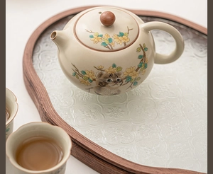 Macro view of Ru kiln teapot with hand-painted yellow flowers and cat on wooden tray