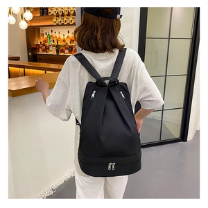 Rear view of model wearing a black Oxford fabric backpack with separate shoe compartment