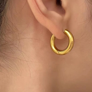 Close-up of thick gold-plated hoop earrings with a high-polished mirror finish