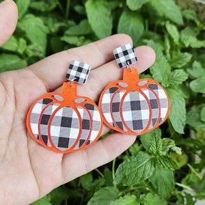 Exaggerated orange pumpkin drop earrings with black and white buffalo plaid pattern