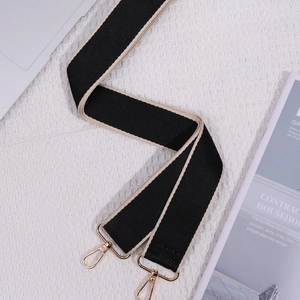 Ethnic style black and beige woven wide shoulder strap with golden metal hooks on a white background