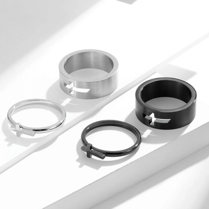Detail view of hollow cross stainless steel rings set on white geometric blocks