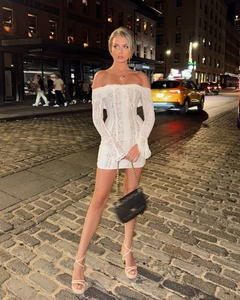 Detail of white lace off-shoulder mini dress with long flared sleeves and textured embroidery