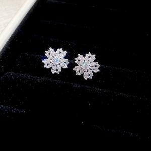 Macro shot of silver snowflake earrings with cubic zirconia in black velvet box