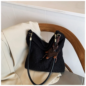 Detail of black knit shoulder bag on a wooden chair with a cute brown dog charm