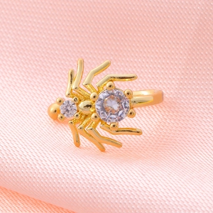 Macro detail of golden spider jewelry featuring sparkling zircons on pink fabric